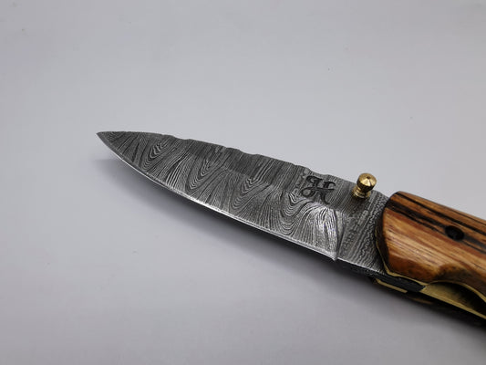 Gros plan sur la pointe et le veinage de la lame en acier damas du couteau Le Santonier – Hosteel