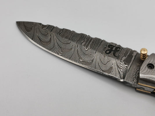 Gros plan sur la pointe et le veinage de la lame en acier damas du couteau Le Tramontane – Hosteel