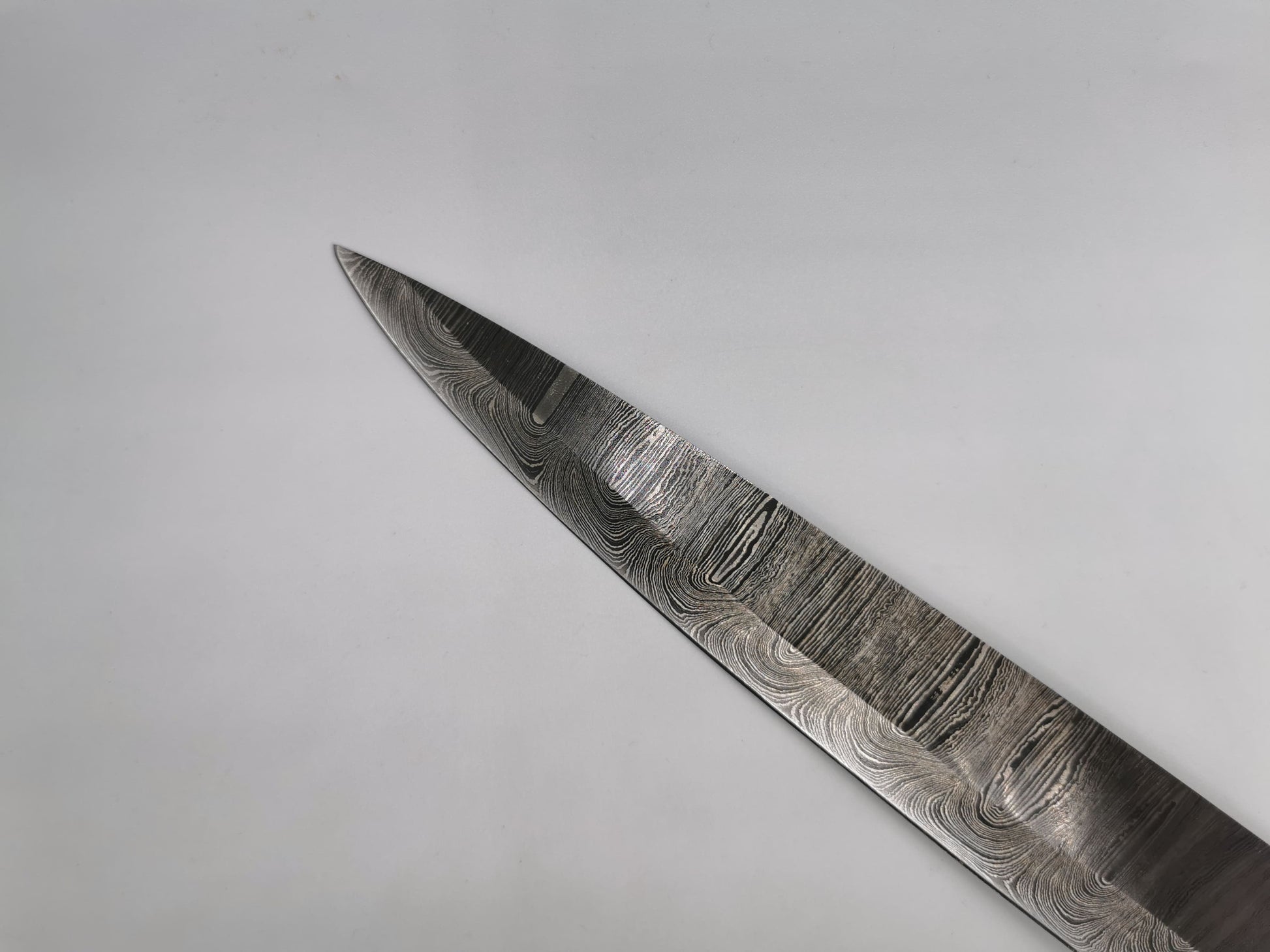 Pointe de la lame en acier damas 1095 et 4340 du couteau de chef Le Valensola, détail du veinage Damas