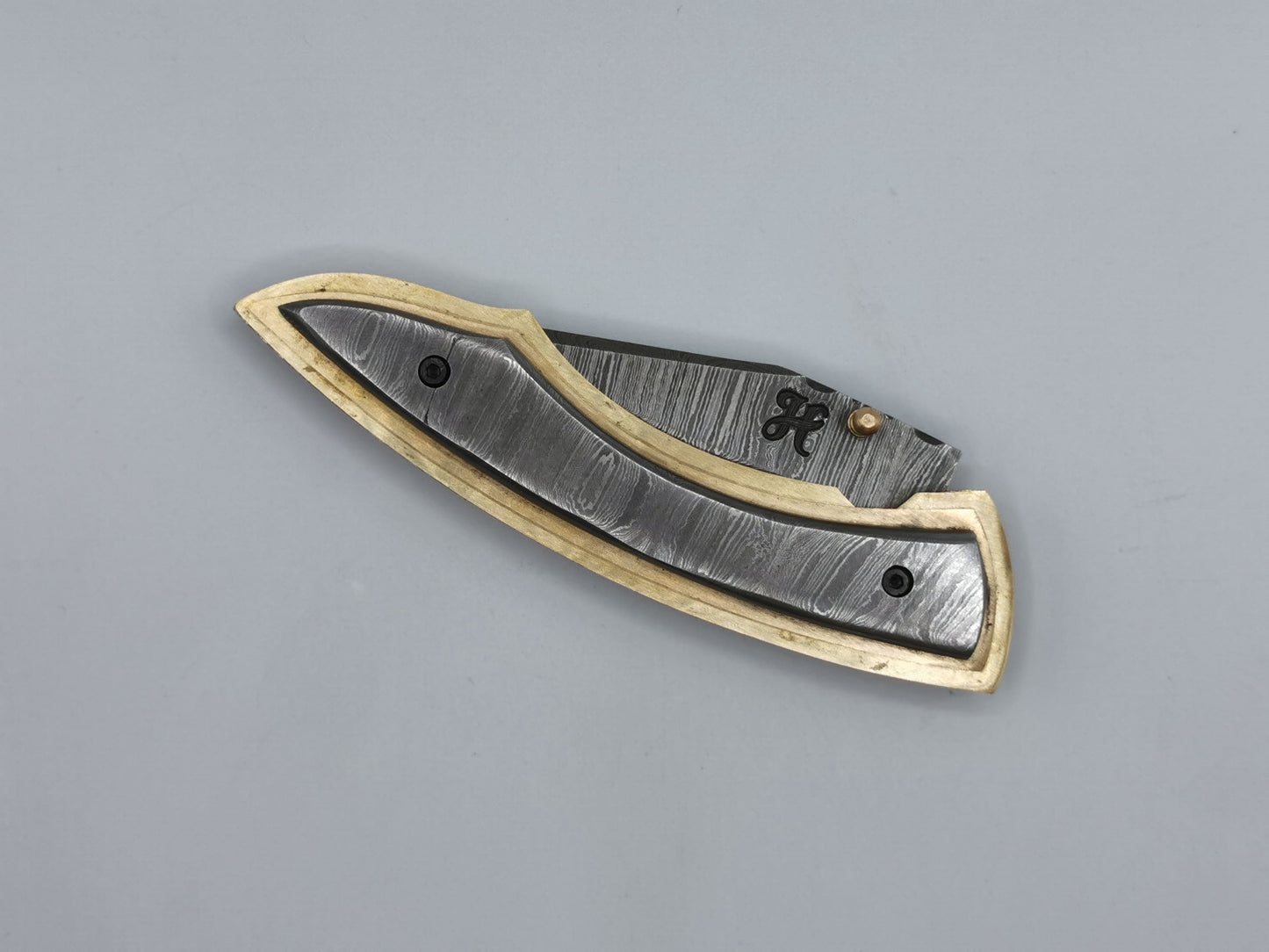 Couteau de poche Le Olympe fermé, vue de dessus, manche acier damas et laiton guilloché