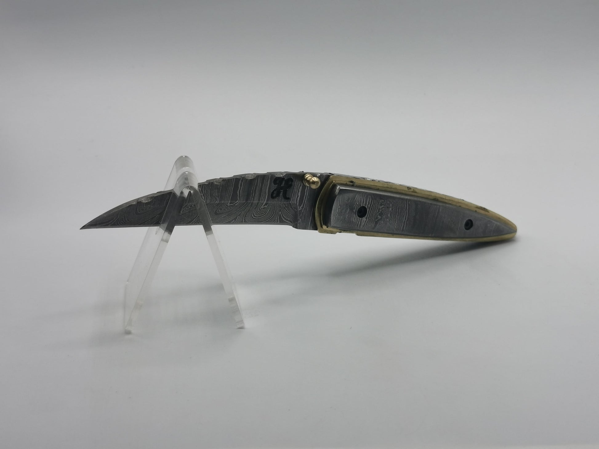 Vue latérale du couteau Le Ferranel sur présentoir, profil acier damas et laiton
