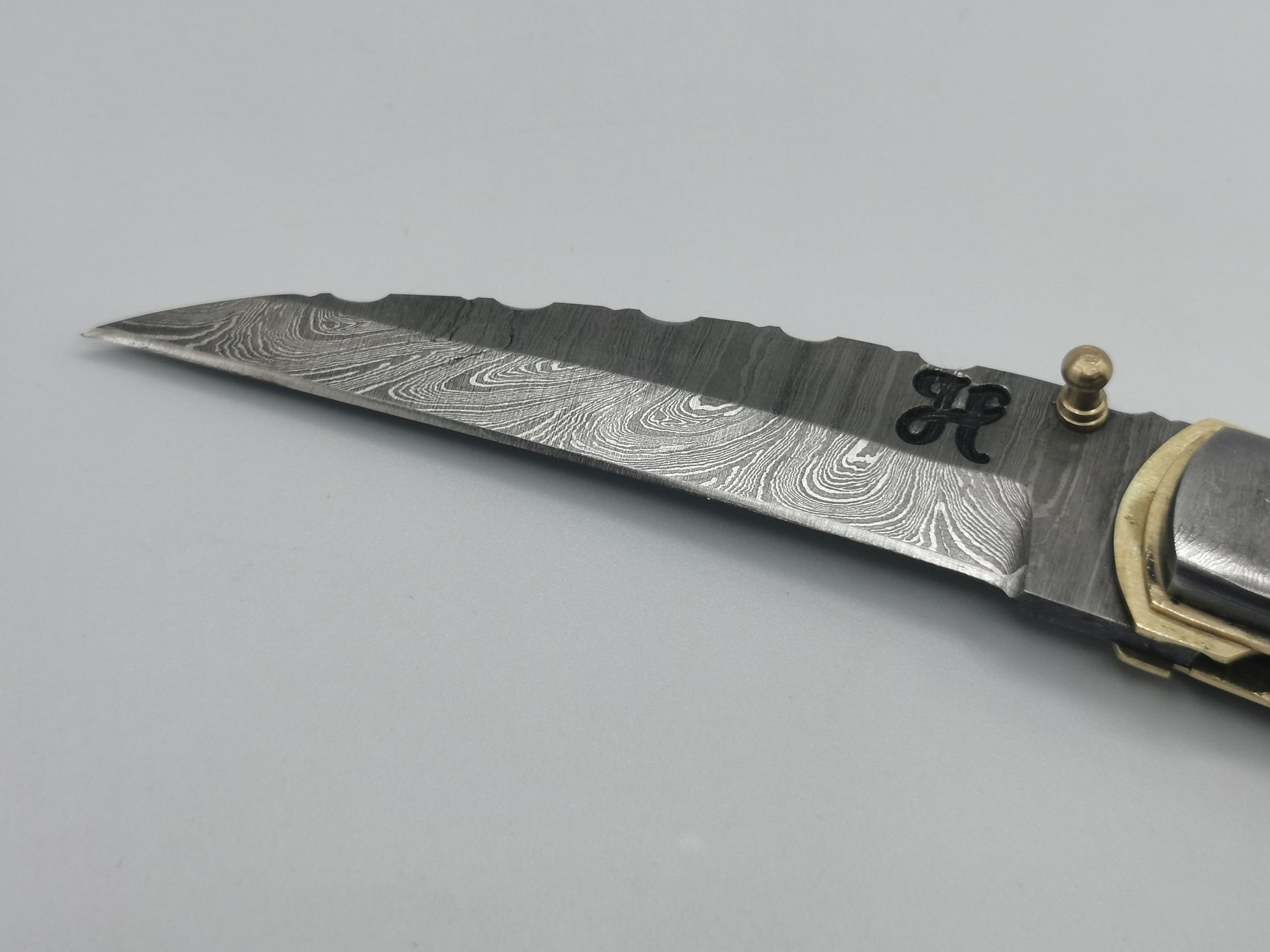 Gros plan sur la pointe de lame damas et le logo Hosteel du couteau Le Ferranel