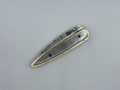 Détail du talon du manche en acier damas, finitions laiton du couteau Le Ferranel