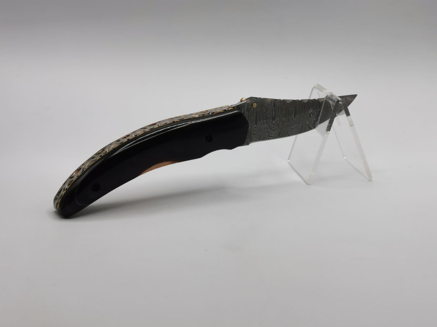 Couteau de poche Le Levan sur présentoir, gros plan sur la lame en acier damas et le manche en corne