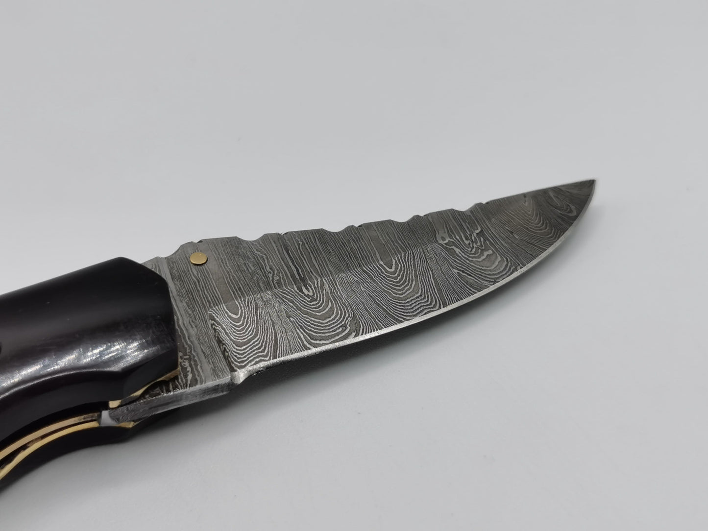 Gros plan sur le talon de lame et la mitre en acier damas du couteau Le Levan – Hosteel