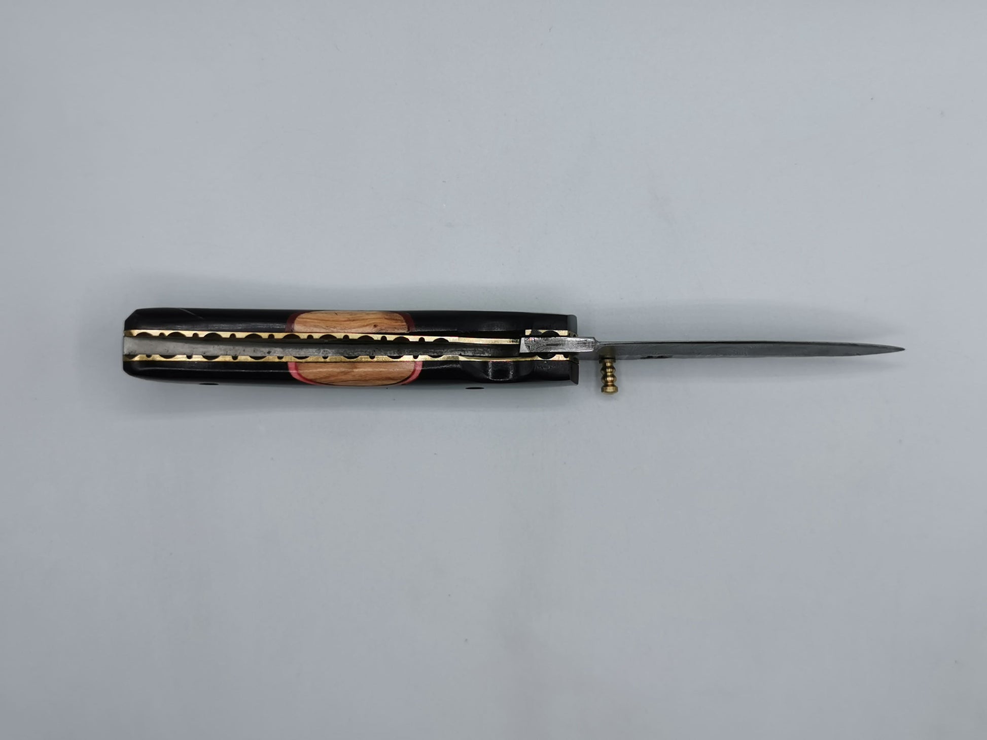 Couteau Le Levan ouvert, vue allongée sur la lame en acier damas et le liseré laiton du manche
