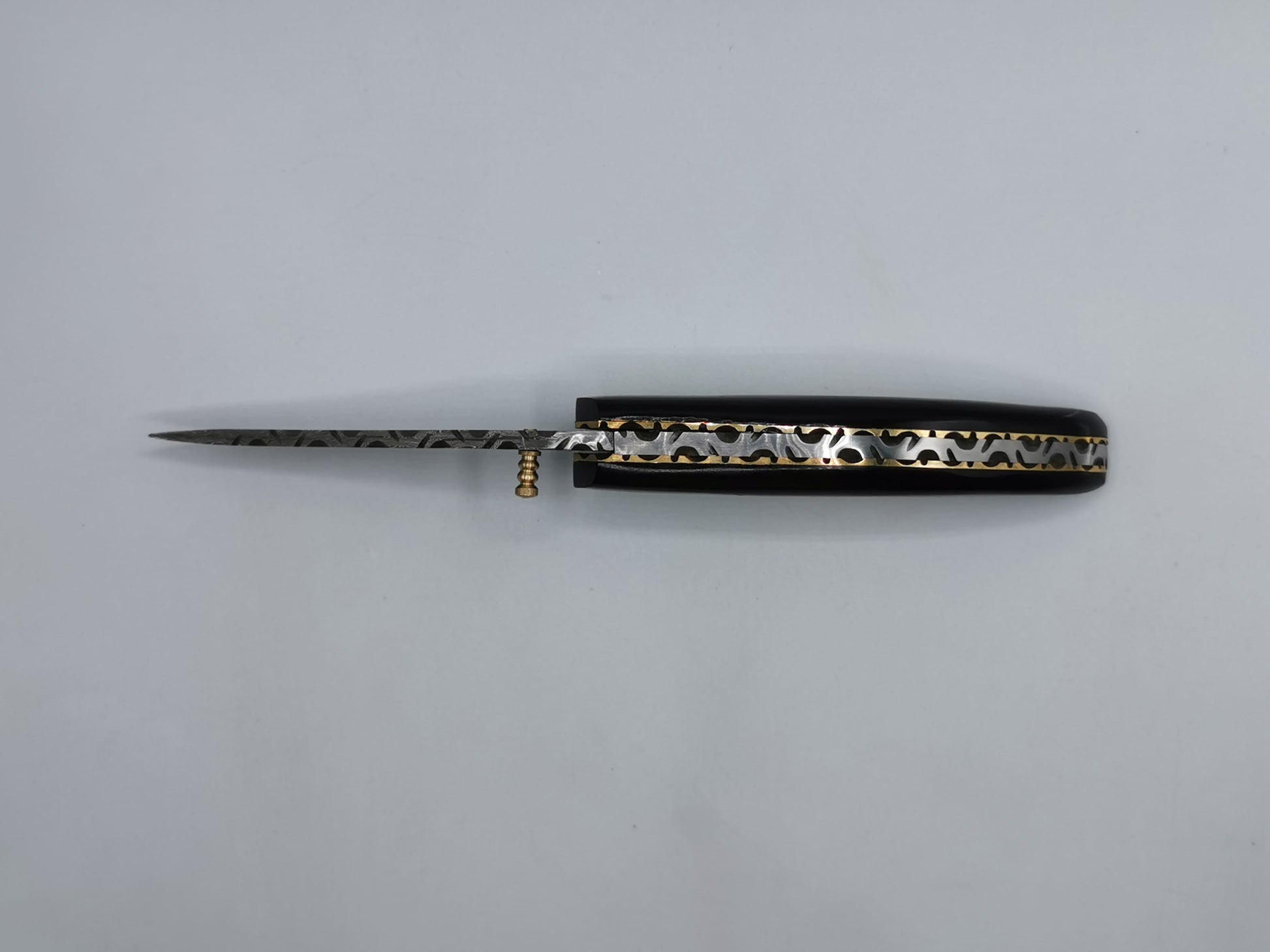 Couteau Le Levan fermé, vue de dessus du manche en corne noire avec liseré laiton ondulé