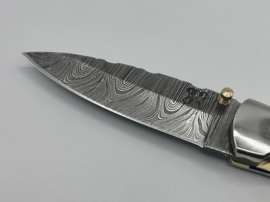 Gros plan sur la pointe de lame damas et le logo Hosteel du couteau Le Luberon

