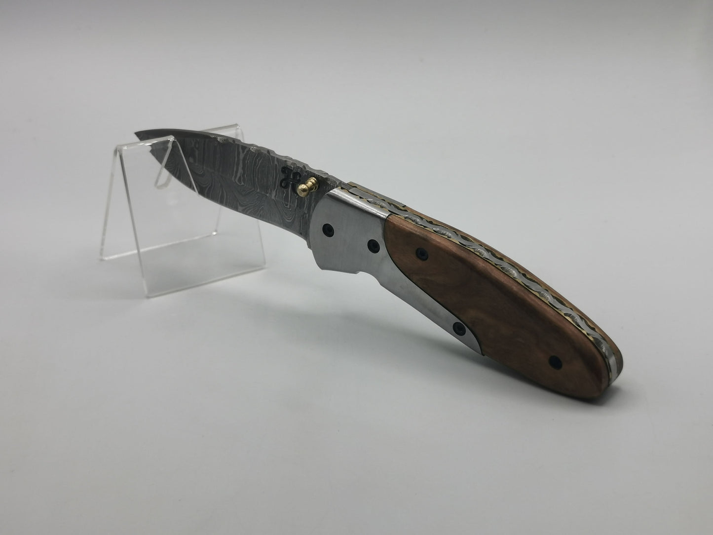Couteau Le Pagnol présenté sur socle, lame damas ouverte et manche robuste
