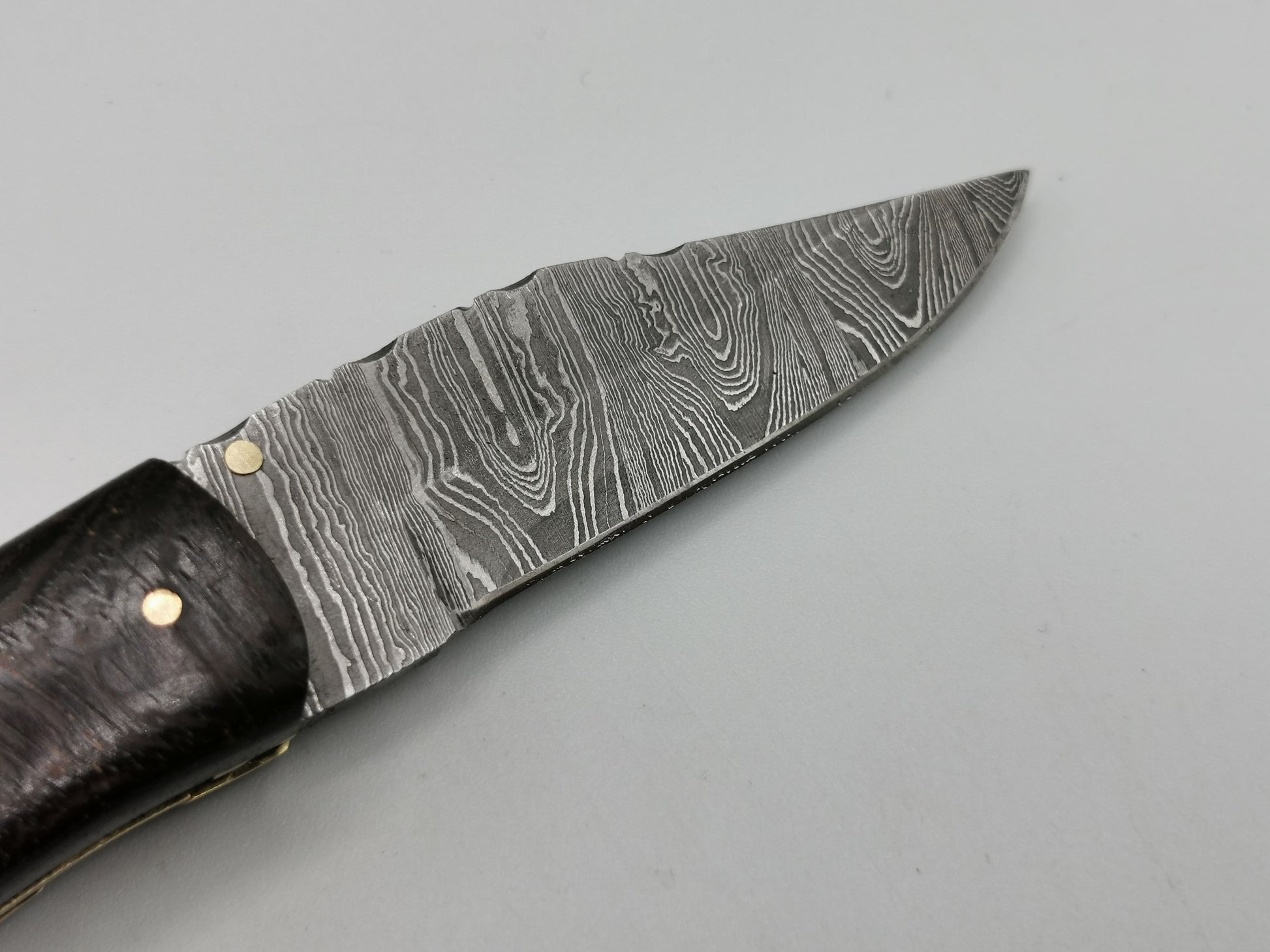 Détail pointe lame damas trempée 62 HRC couteau pliant Le Roucas