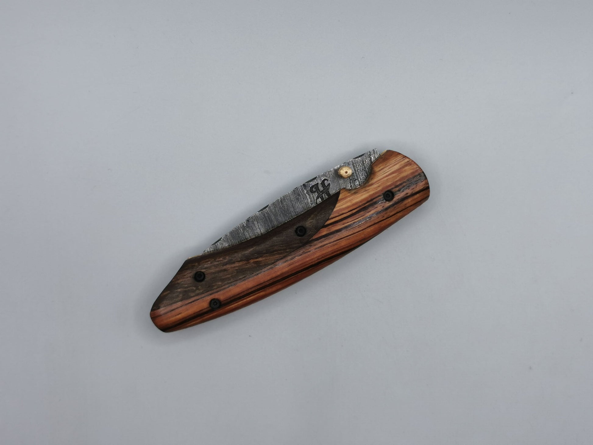 Couteau Le Santonier ouvert, vue allongée sur la lame en acier damas et la mitre en laiton