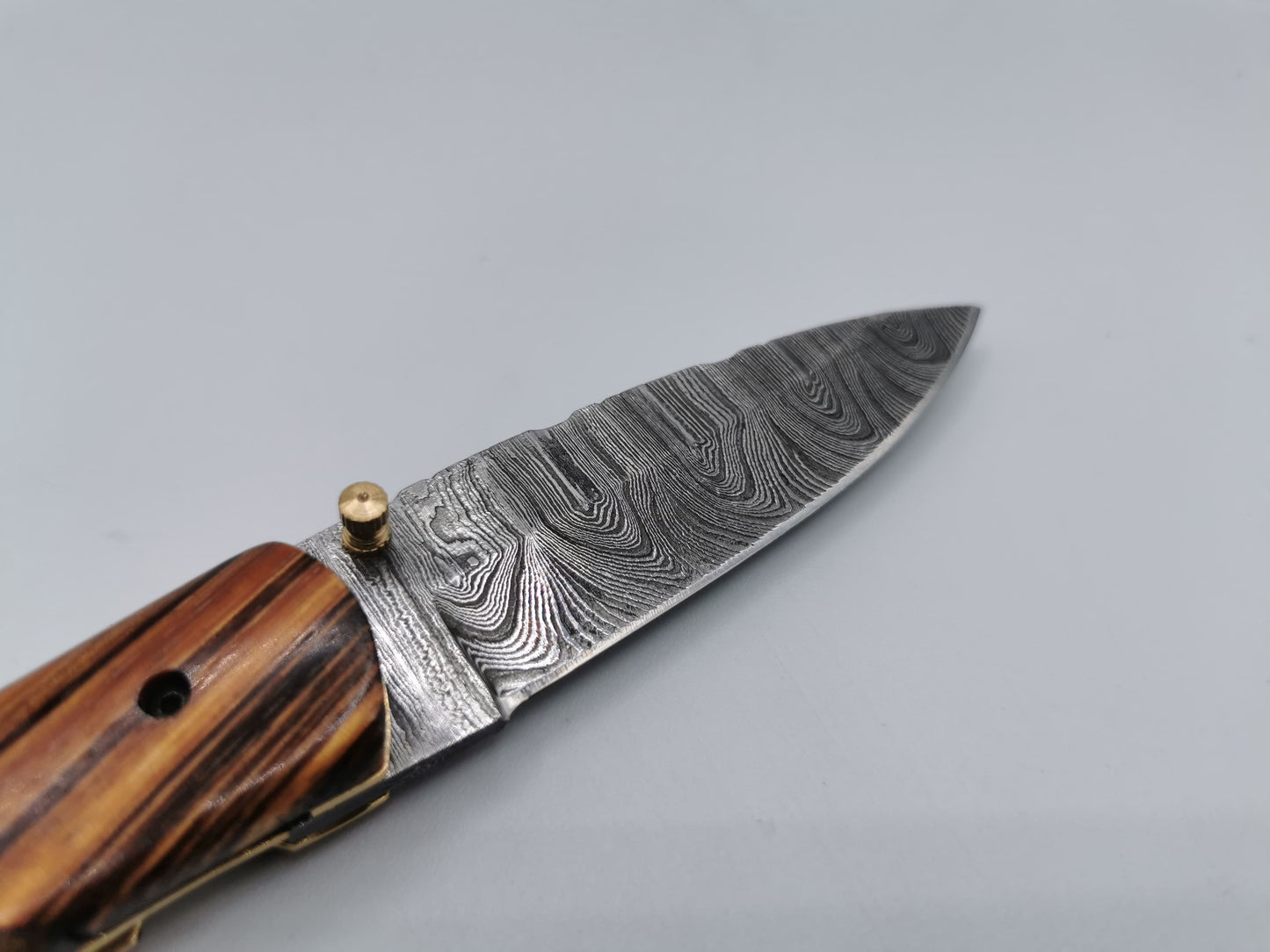 Gros plan sur le talon de lame et la mitre en acier damas du couteau Le Santonier – Hosteel