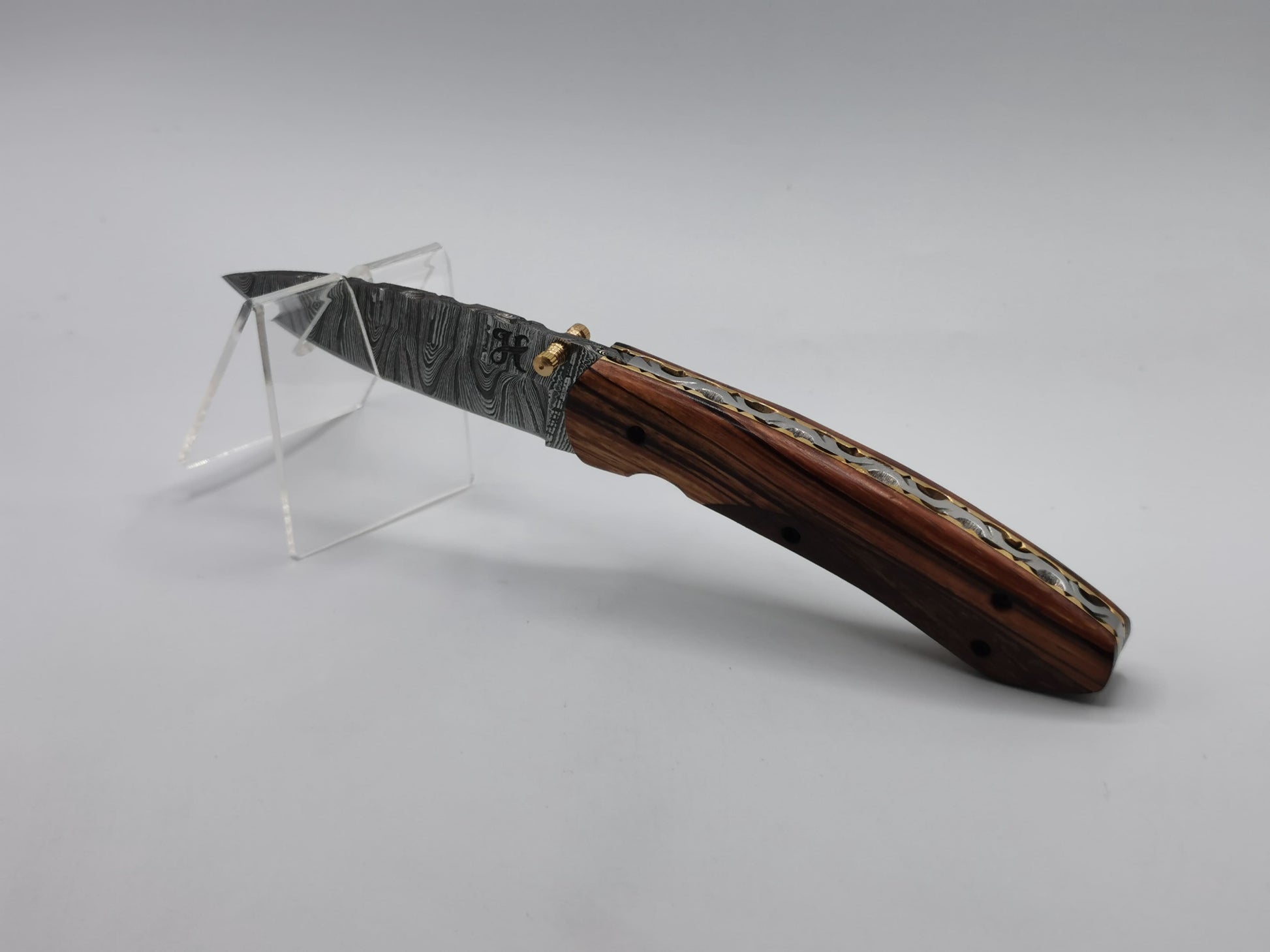 Couteau de poche Le Santonier sur présentoir, gros plan sur la lame en acier damas et le manche en bois
