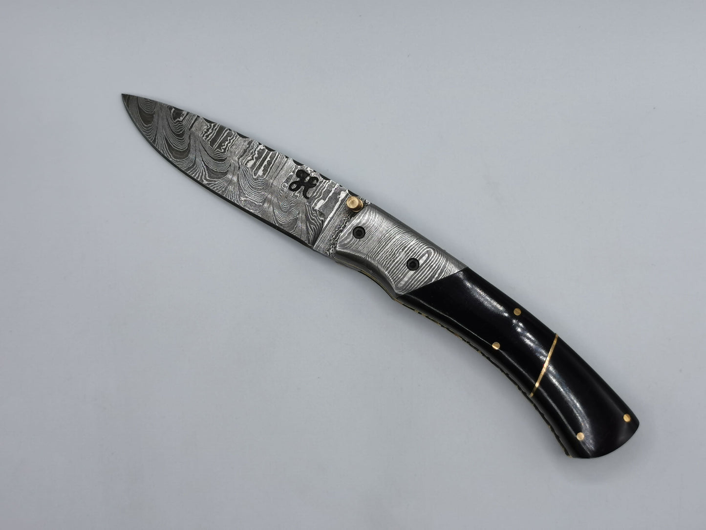 Couteau de poche en acier damas Le Tramontane ouvert, lame en acier damas et manche en corne de buffle rehaussé de laiton – Hosteel