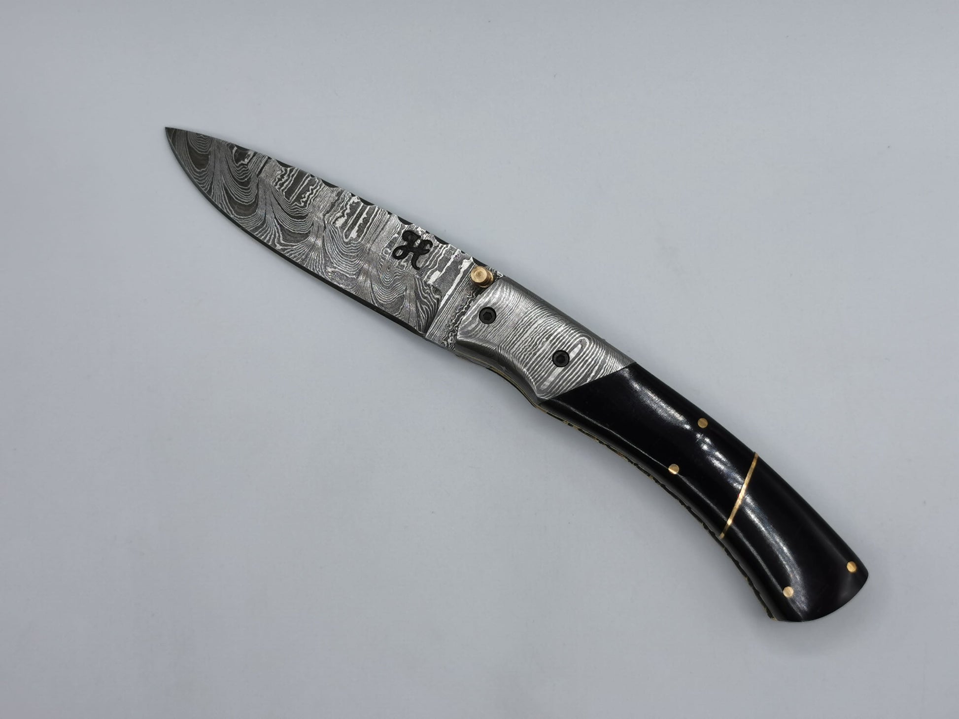 Couteau de poche en acier damas Le Tramontane ouvert, lame en acier damas et manche en corne de buffle rehaussé de laiton – Hosteel