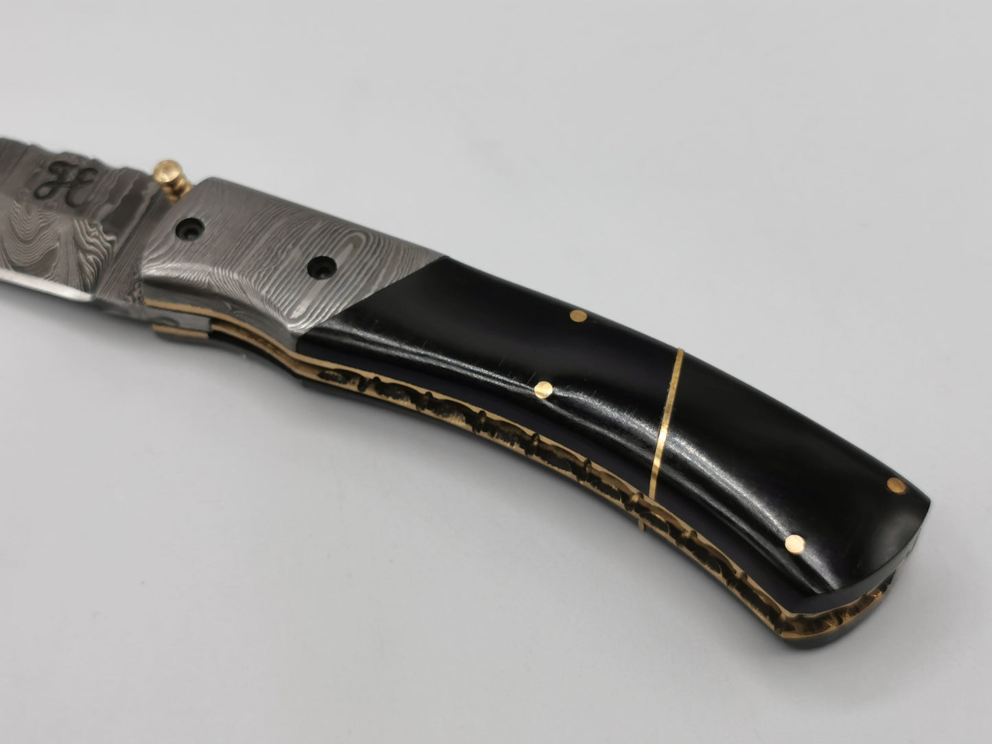 Détail du manche du couteau Le Tramontane : insert en acier damas, corne de buffle et filet laiton