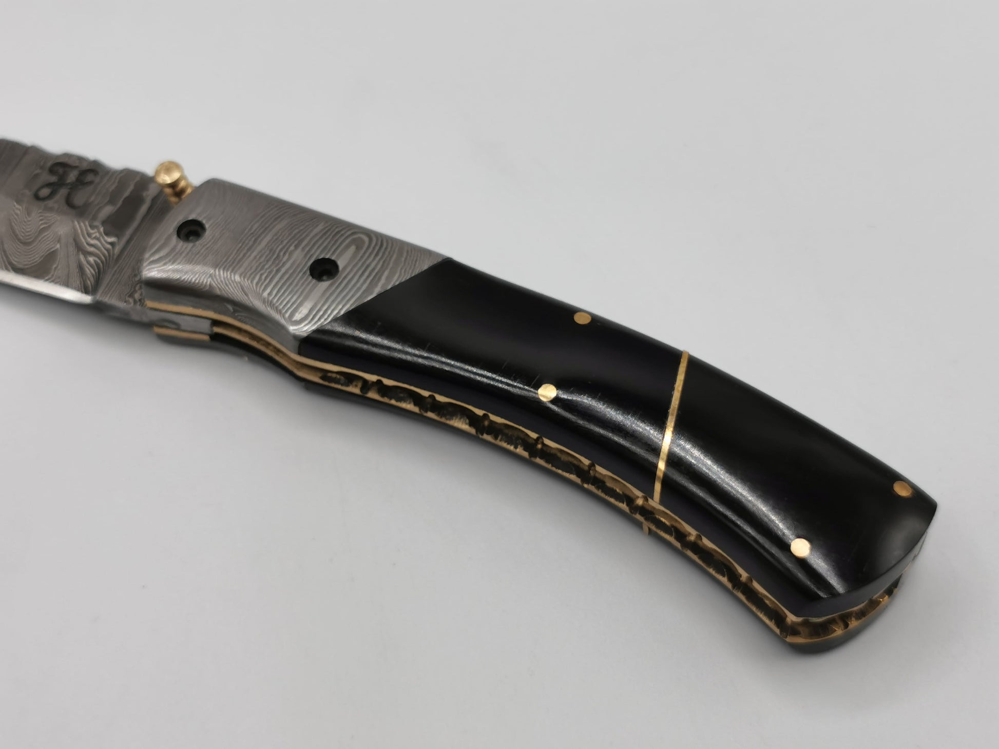 Détail du manche du couteau Le Tramontane : insert en acier damas, corne de buffle et filet laiton
